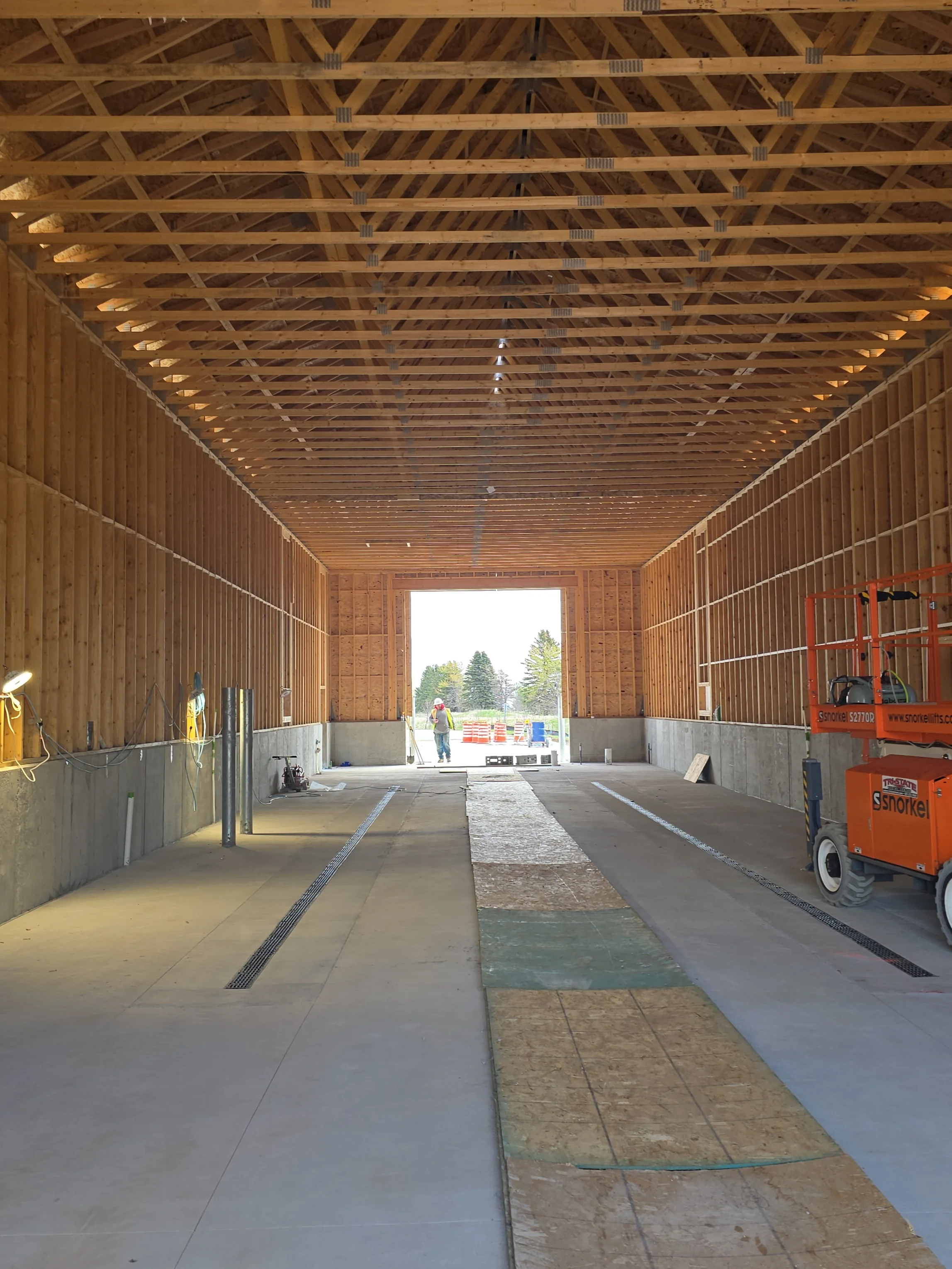 Interior of newly constructed agricultural building with exposed wood trusses and concrete floor