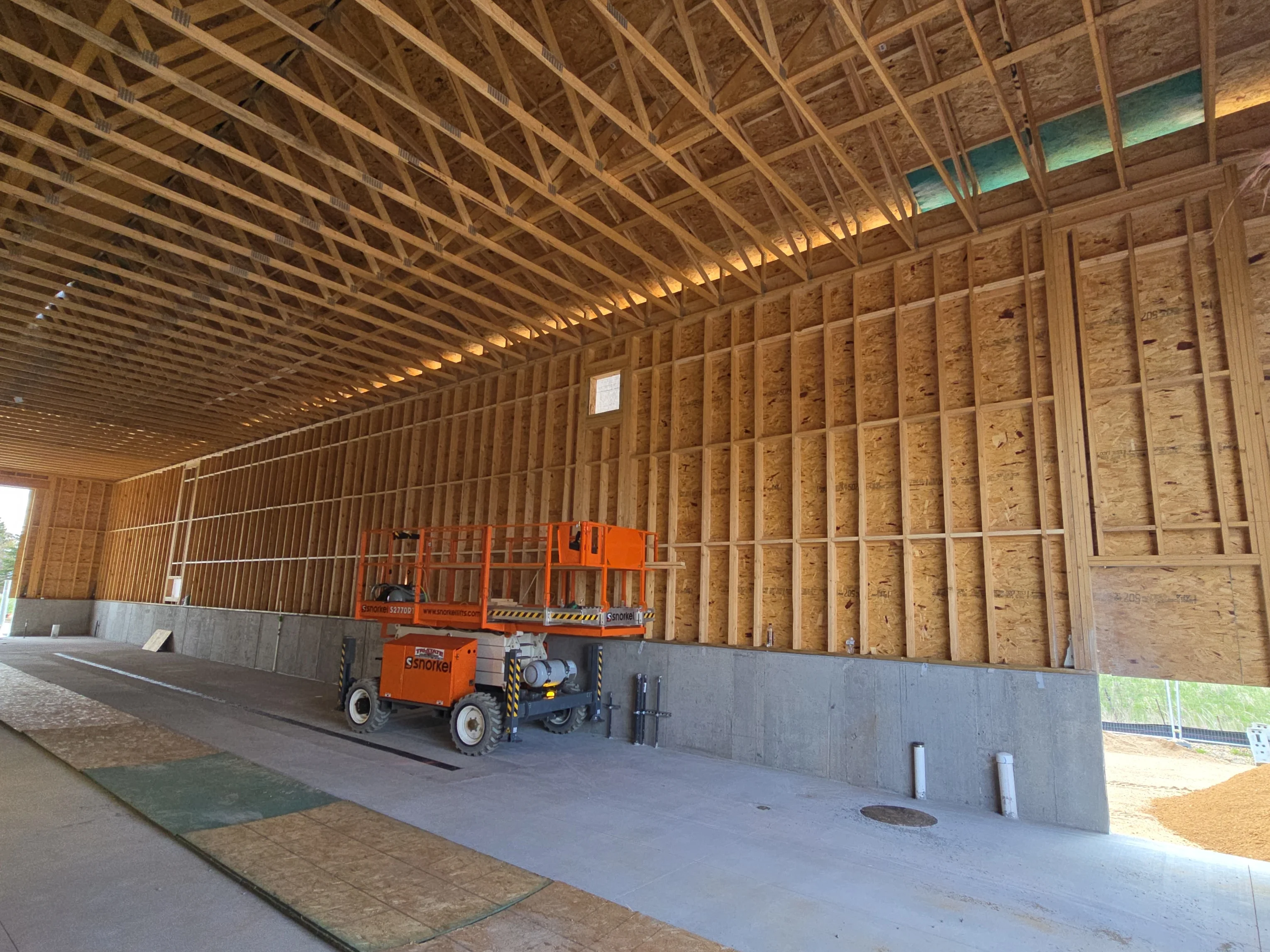 Interior of new agricultural building with wood framing, metal roof, and concrete foundation